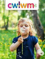 Girl wearing a navy blue top in a field of Dandelions. Text reads: Cwlwm Newsletter, Spring Term 2023